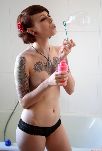 Молодая девочка с татуировками показывает голое тело